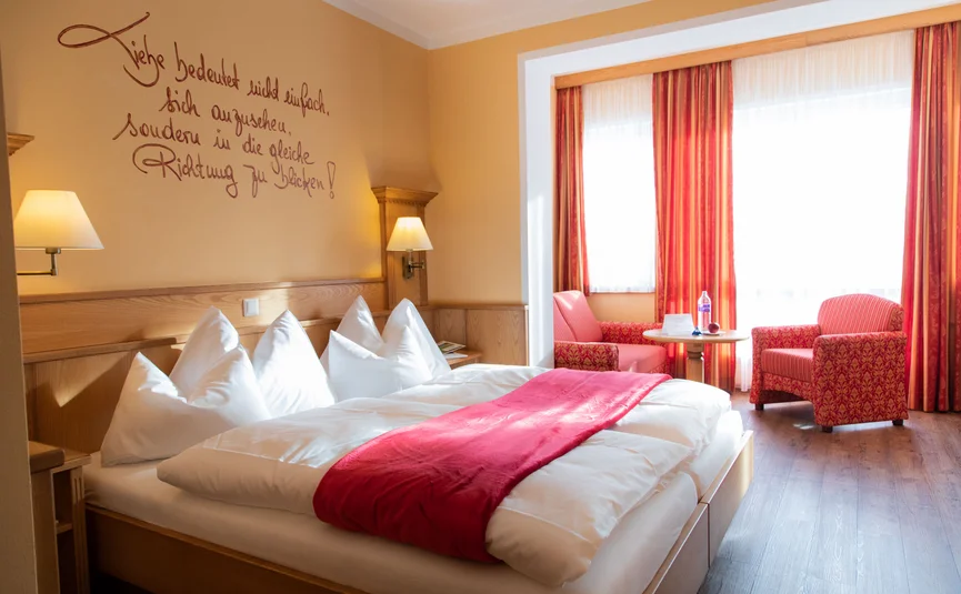 Gemütliches Hotelzimmer mit Doppelbett und rotem Bettläufer