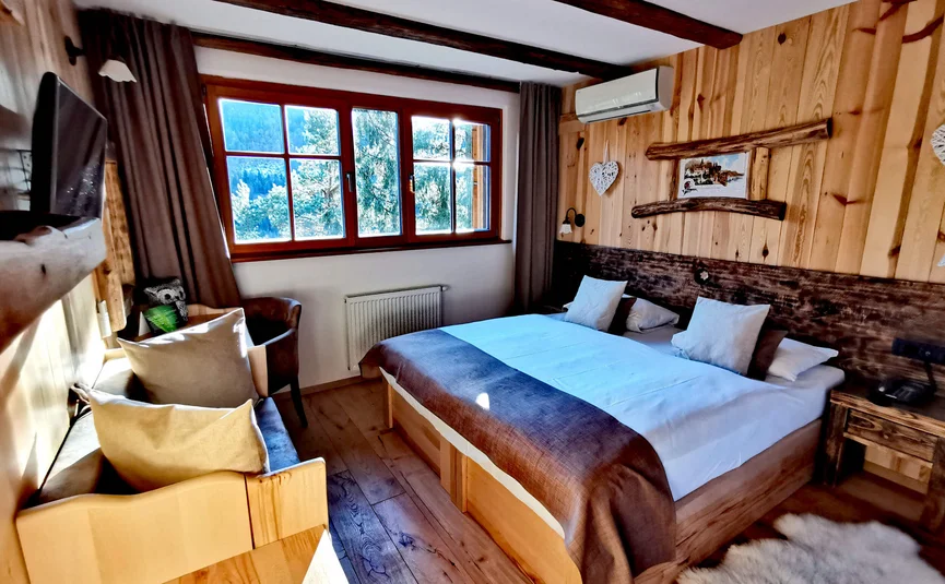 Cozy bedroom with wooden decor, large bed, and window showing mountain view