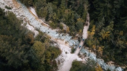 Luftaufnahme von Wanderern auf einer Brücke über einen Fluss im Wald