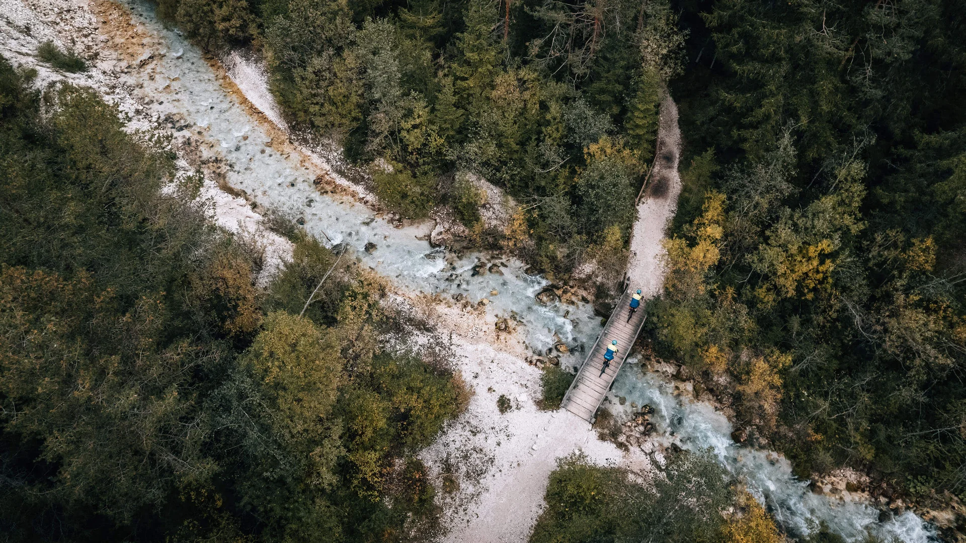 Herbst auf Schotter im Excelsior Dolomites Life Resort****s © Jens Scheibe Luftaufnahme von Wanderern auf einer Brücke über einen Fluss im Wald