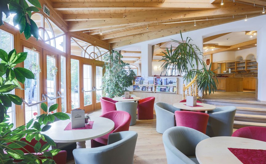 Helles Café mit roten und grauen Sesseln und vielen Pflanzen