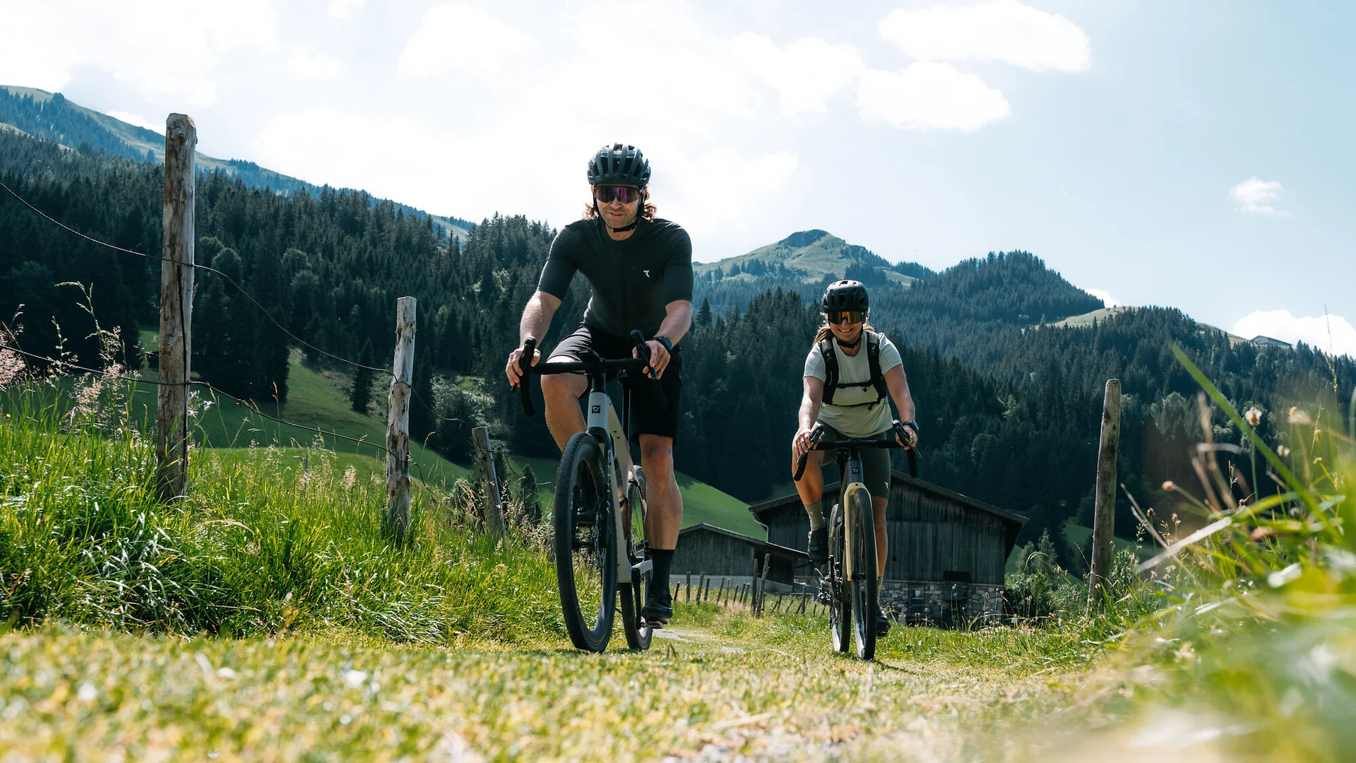 Graveln in den Kitzbüheler Alpen © Martina Wunderle / Flo Distl Zwei Radfahrer fahren auf einem Weg in den Bergen bei sonnigem Wetter