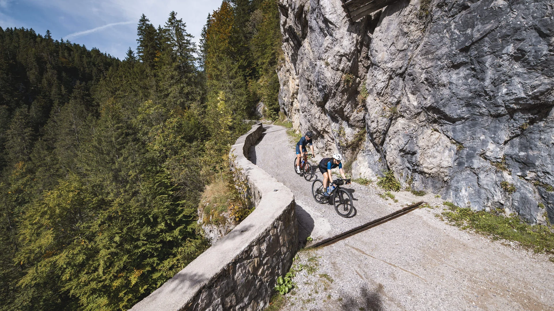 Zwei Radfahrer fahren auf einem Bergweg neben einer Felswand