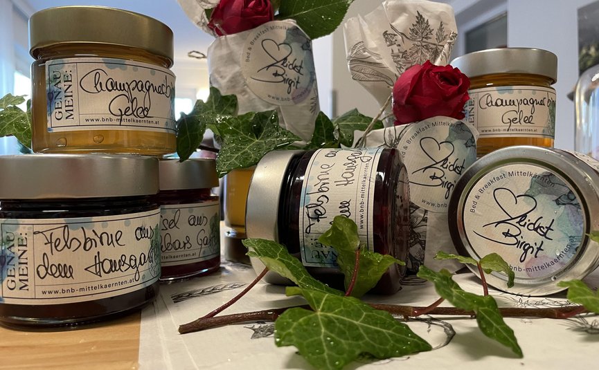 Verschiedene Marmeladen und Gelees mit Rosen und grünen Blättern dekoriert