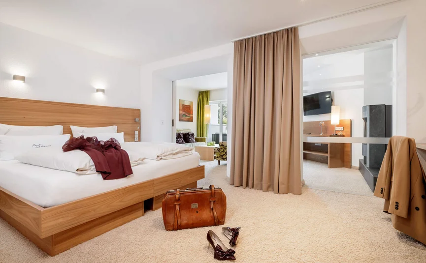 Modernes Hotelzimmer mit Doppelbett, Ledertasche und High Heels auf beigem Teppich