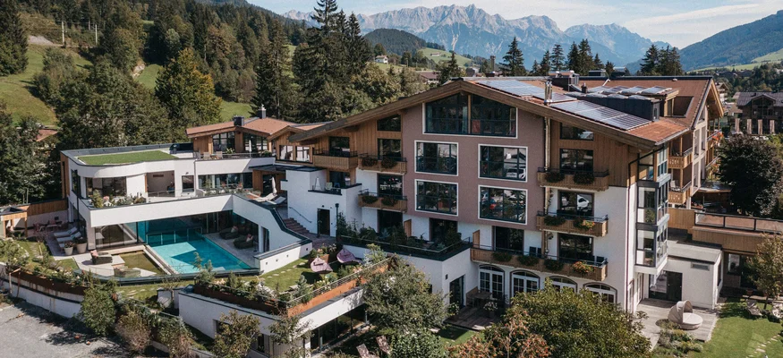 Hotel mit Schwimmbad vor Berglandschaft und Wald