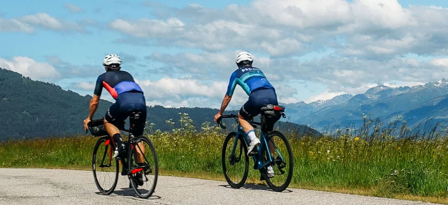 Austria Giro unsupported © Hotel Melodia del Bosco Zwei Radfahrer fahren auf einer Straße mit Bergblick bei klarem Himmel