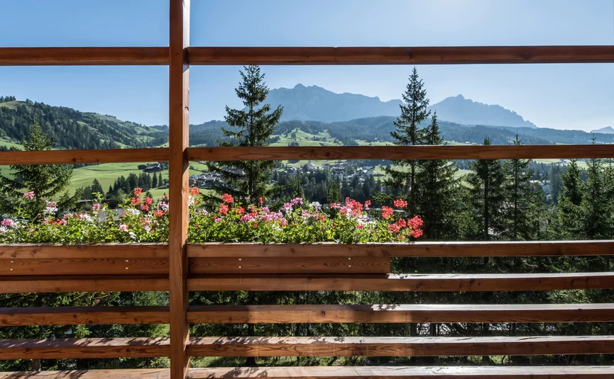 Blick auf Berge und Blumen von einem Balkon mit Holzgeländer