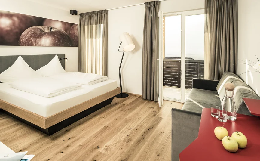Modern hotel room with double bed, sofa, and balcony