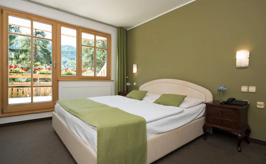 Bedroom with green-accented bed and view of trees through the window