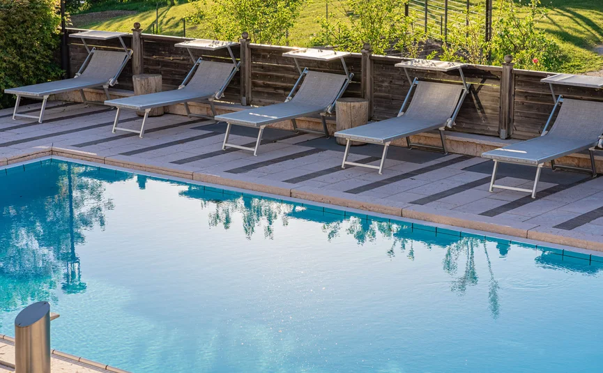 Cristallo Sport & Wellness Hotel **** © Andrea Acler Swimming pool with lounge chairs and wooden fence in sunny weather