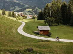 Alta Badia © Alex Moling Two cyclists on a path in a green valley with mountains in the background