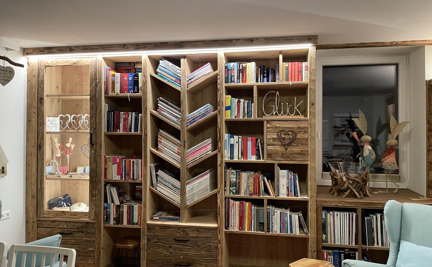 Holzregal mit Büchern und Zeitungshaltern in einem gemütlichen Wohnzimmer