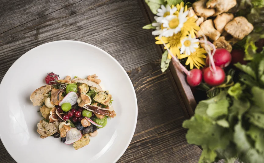 Excelsior Dolomites Life Resort ****S © Hannes Niederkofler Salat mit Pilzen, Beeren und Kräutern auf weißem Teller nahe frischem Gemüse