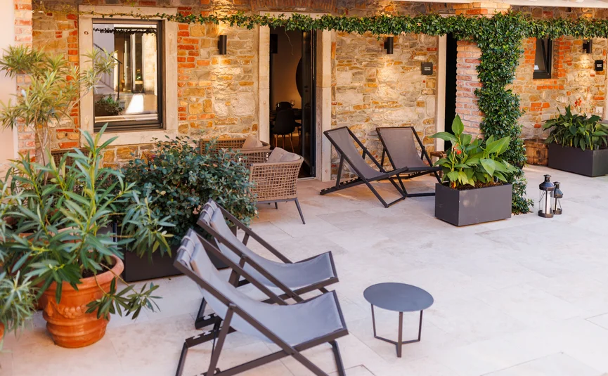 Terrace with deck chairs, plants, and stone wall illuminated warmly