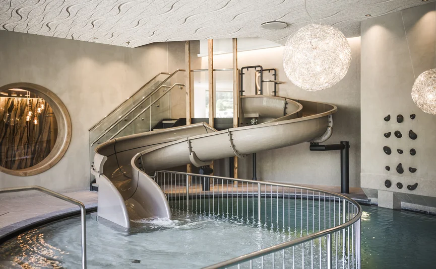 Indoor slide leading into a swimming pool with modern lighting