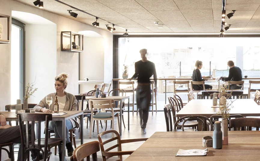 Moderner Caféinnenraum mit Gästen und Kellner in Bewegung