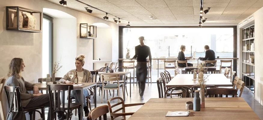 Müde Beine, volle Bäuche, offene Herzen © Hotel Bären - Cafe Deli Mellau Moderner Caféinnenraum mit Gästen und Kellner in Bewegung