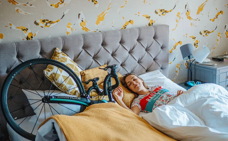 Woman sleeping in bed next to a bicycle in a room with koi fish wallpaper
