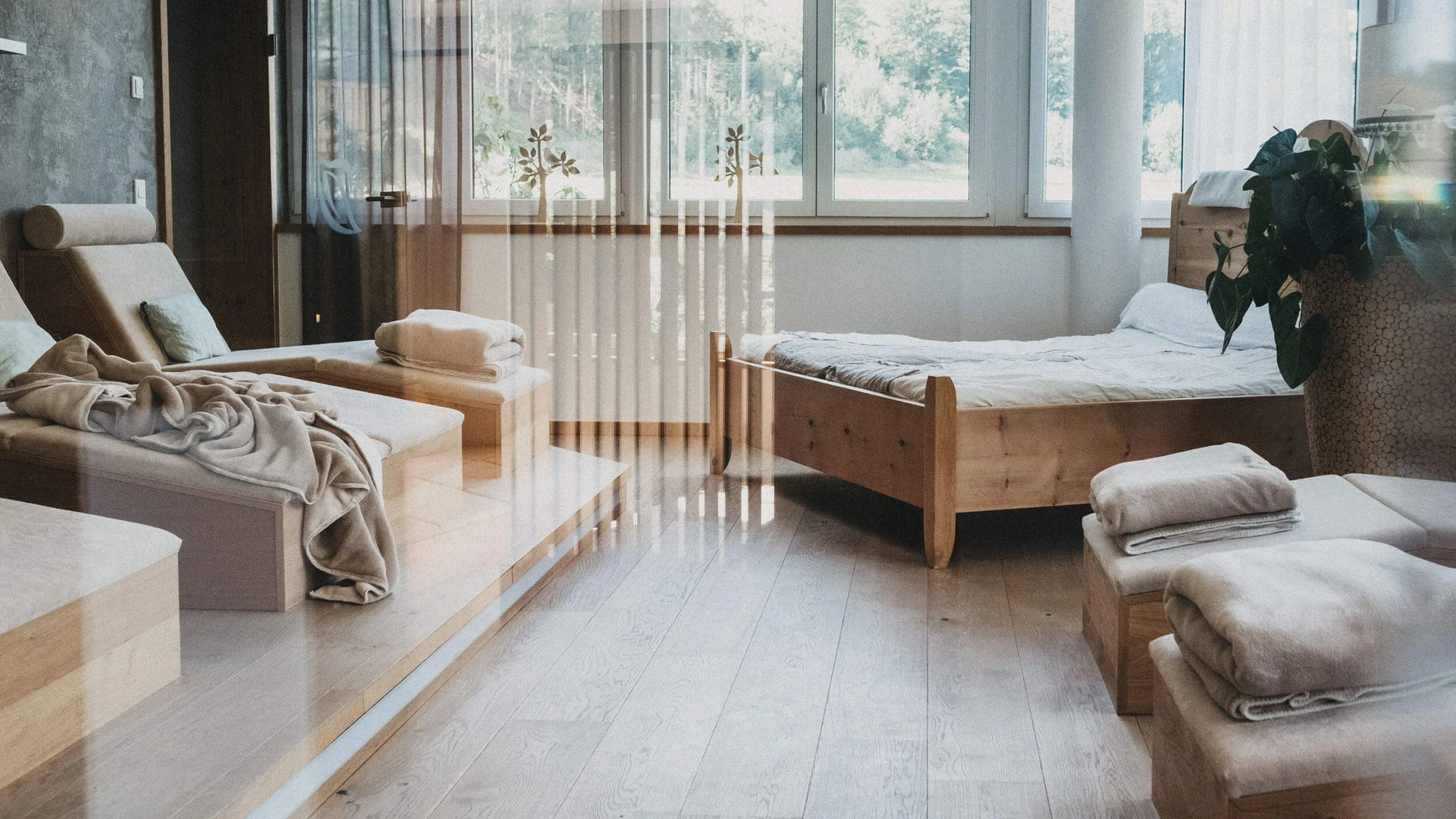 Helles Schlafzimmer mit Holzmöbeln, Bett und Fenster mit Blick ins Grüne