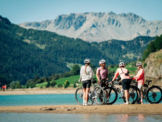 Das waren die Golden Days in Nauders © TVB-Tiroler-Oberland-Nauders-Christian-Penning - Gravelbikerinnen in Nauders-Reschenpass Vier Radfahrerinnen mit Fahrrädern am Ufer eines Bergsees