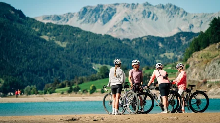 Das waren die Golden Days in Nauders © TVB-Tiroler-Oberland-Nauders-Christian-Penning - Gravelbikerinnen in Nauders-Reschenpass Vier Radfahrerinnen mit Fahrrädern am Ufer eines Bergsees