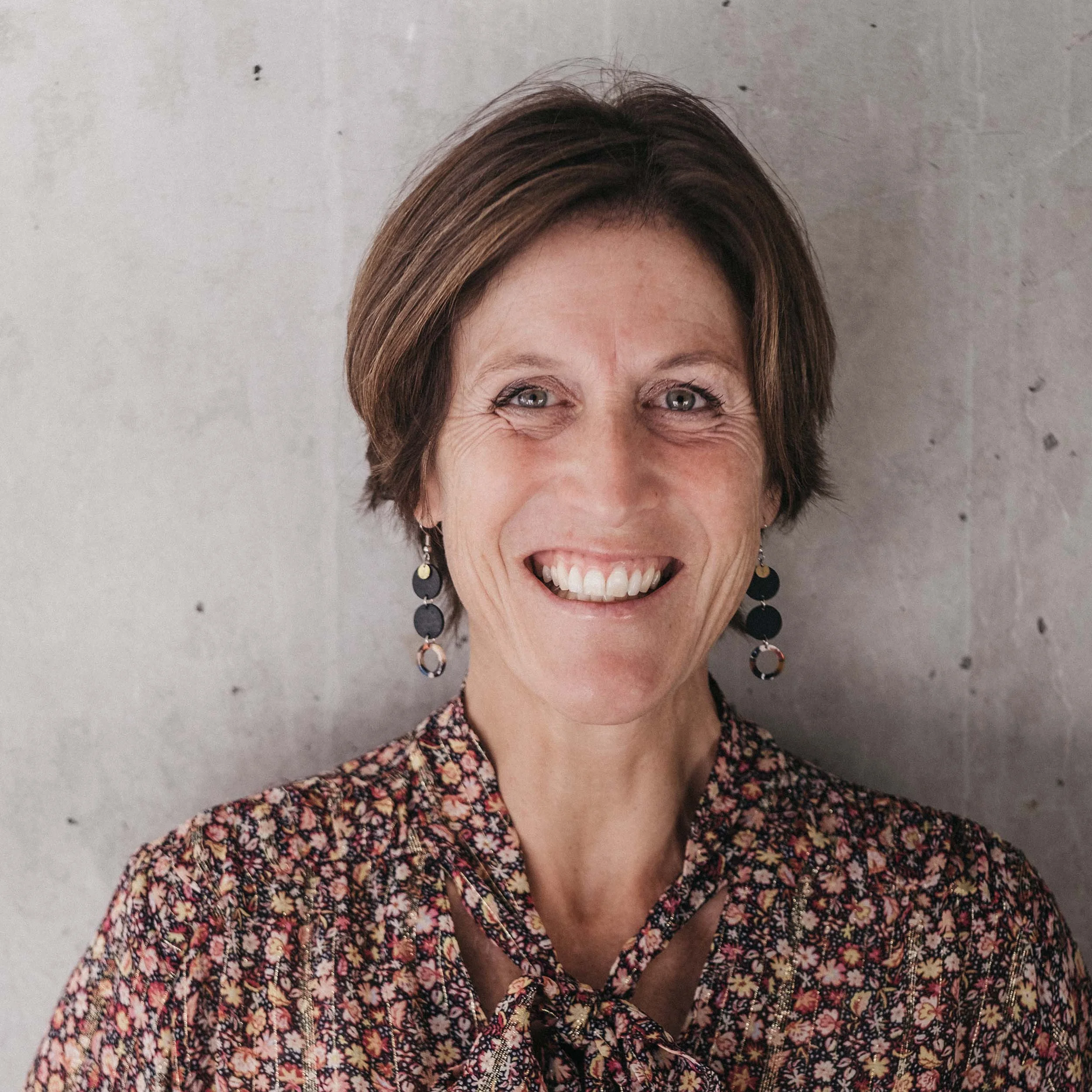 Porträt einer lächelnden Frau mit kurzem Haar und geblümter Bluse