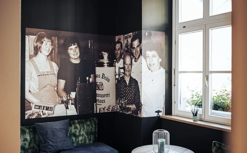 Posthorn Hotel-Restaurant © Dimitri Dell Gemütliche Lounge mit dunklen Wänden, blauen Sitzbänken, rundem Tisch und historischen Schwarzweißfotos