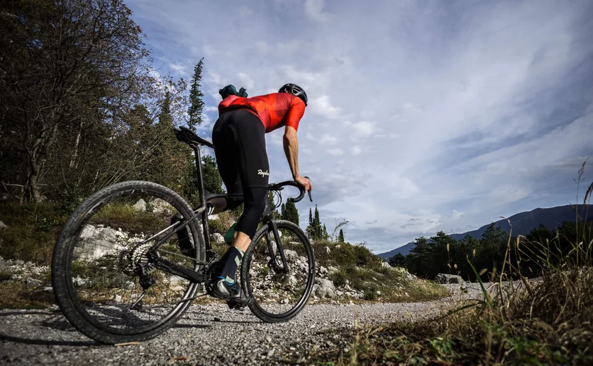 Gravel bike holiday on Northern Lake Garda © Gijs Ferkranus - Wielrenblad Magazine Cyclist in red jersey riding on gravel path in mountainous area