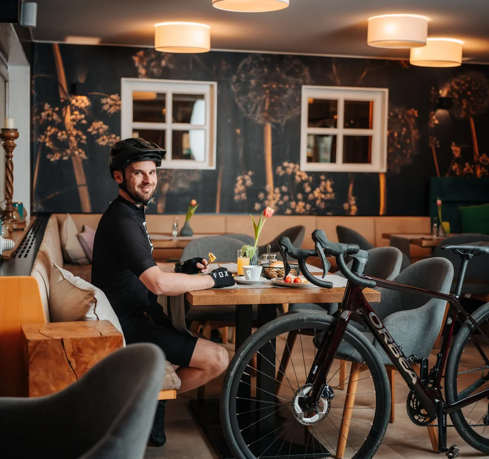 Mann mit Fahrradhelm sitzt in Café und isst