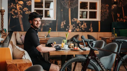 Mann mit Fahrradhelm sitzt in Café und isst