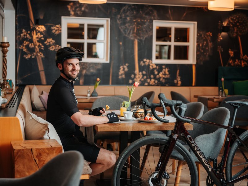 Mann mit Fahrradhelm sitzt in Café und isst