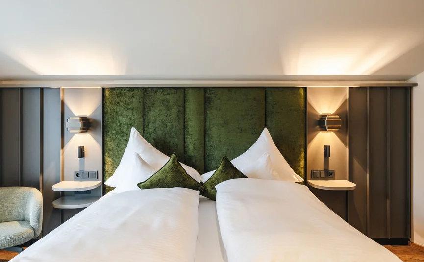 Modern hotel room with green headboard and white bedding