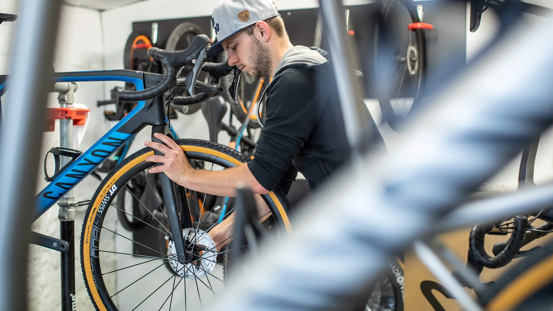 Mann repariert Fahrradreifen in einer Werkstatt mit mehreren Fahrrädern