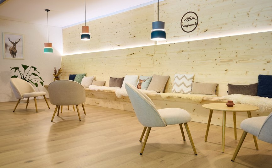 Gemütlicher Sitzbereich mit Holzmöbeln, Kissen und modernen Hängelampen