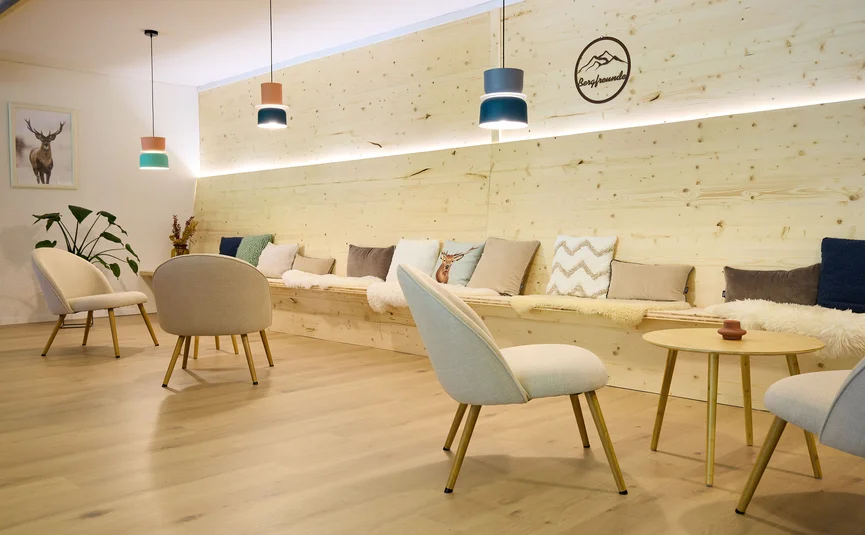 Cozy seating area with wooden furniture, cushions, and modern pendant lights