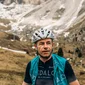 Rennradfahrer mit Helm vor Berglandschaft mit wenig Schnee