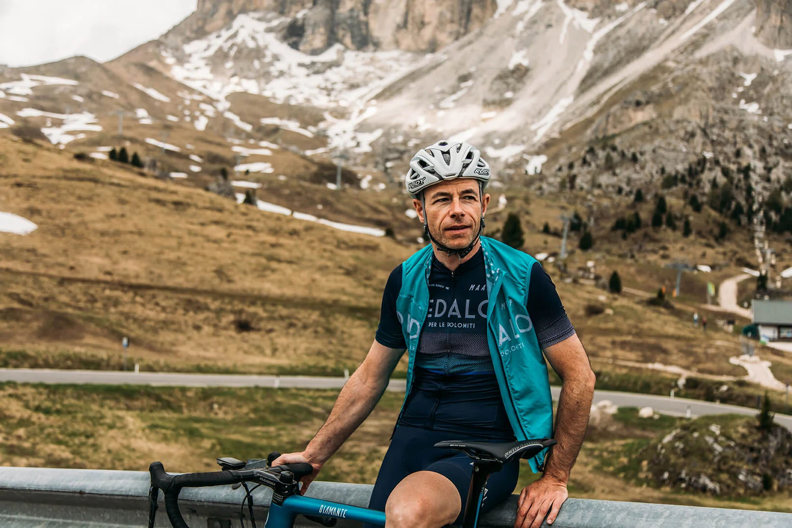 Rennradfahrer mit Helm vor Berglandschaft mit wenig Schnee