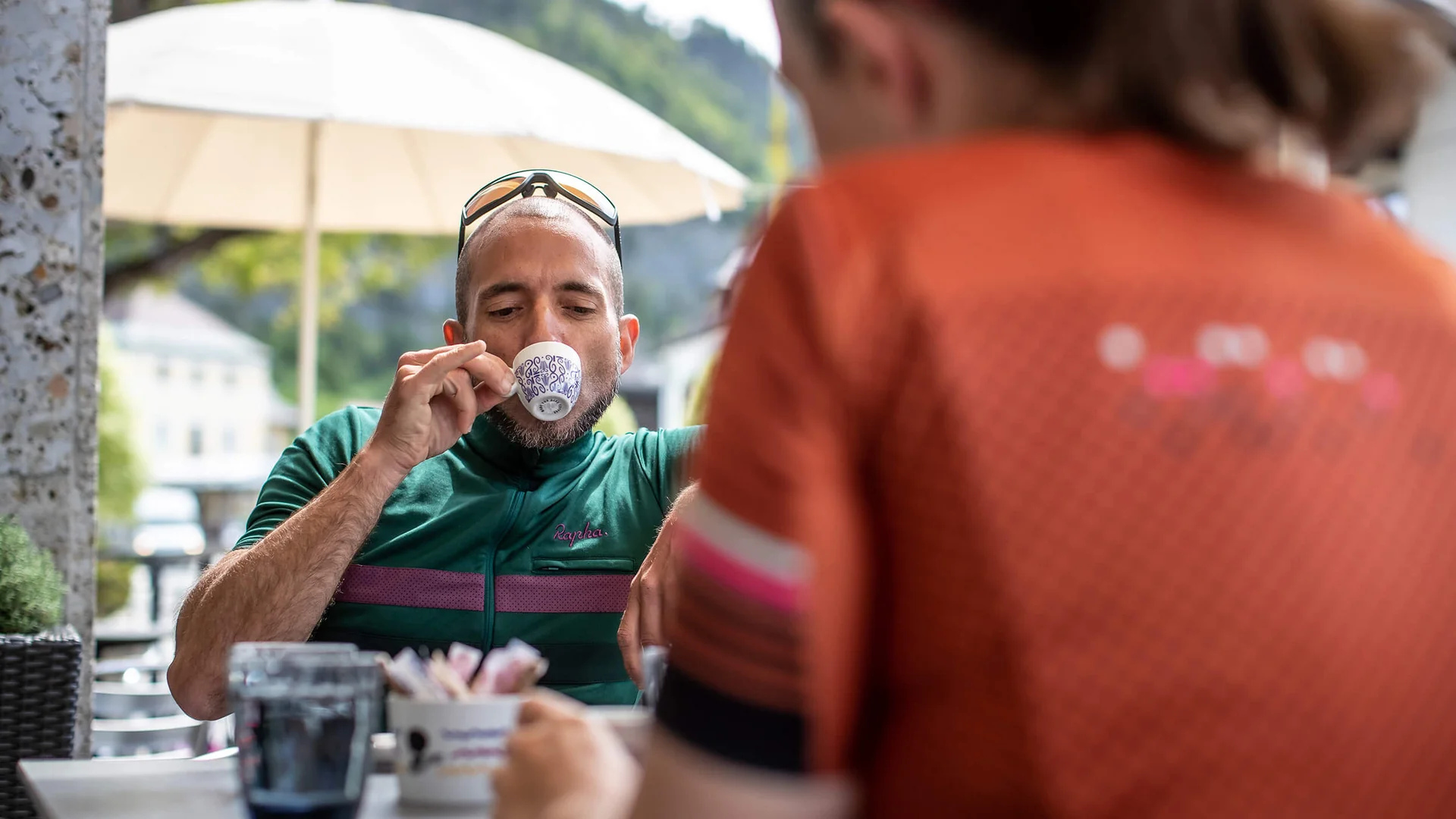 Mann in Sportkleidung trinkt Kaffee in einem Café im Freien