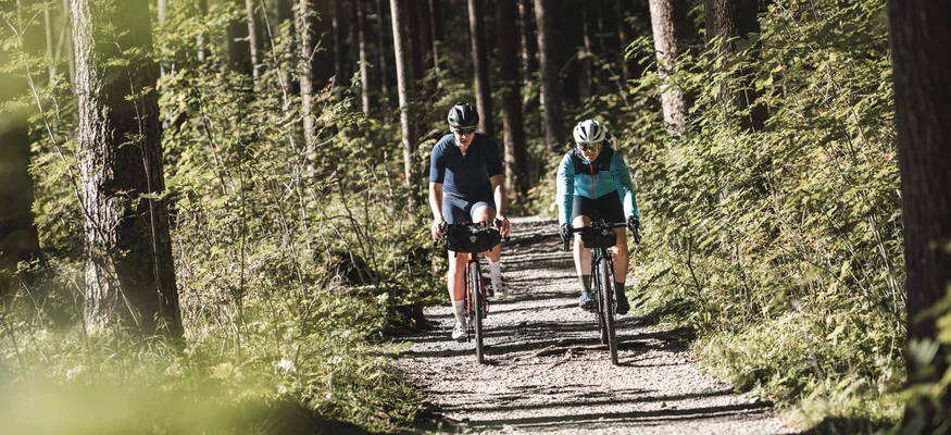 Gravelbike-Wochenende des Jahres:
Ride’n Gravel Testival 2026 © Andreas Vigl Zwei Radfahrer fahren auf einem Waldweg durch dichten grünen Wald