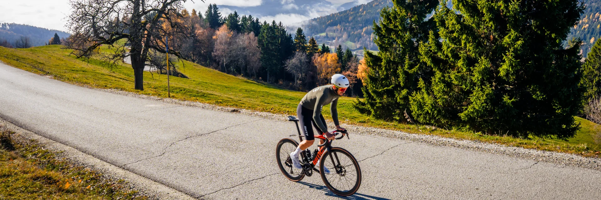 Radfahrer fährt auf Bergstraße bei sonnigem Herbstwetter mit Nebel im Tal