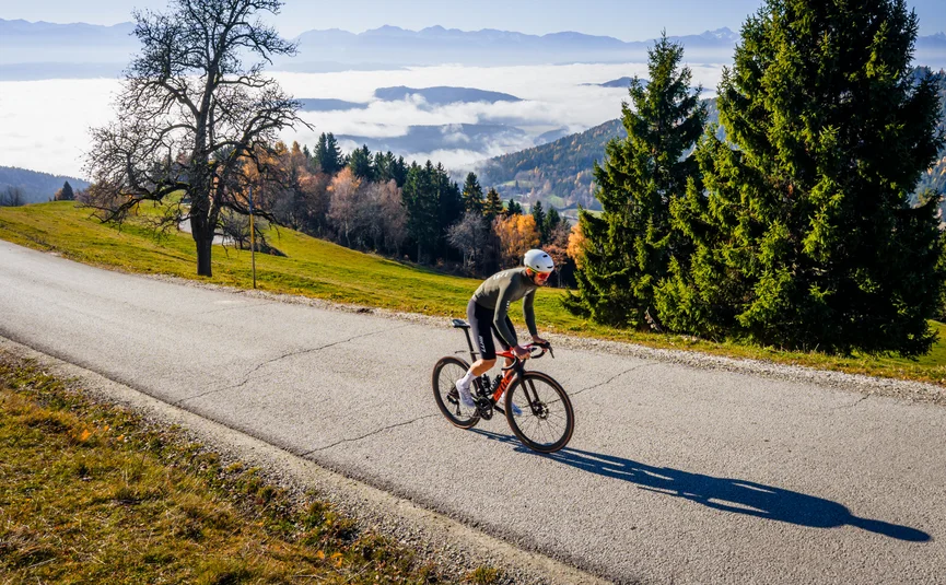 Gravel bike holiday in Central Carinthia © Michael Stabentheiner Cyclist rides on mountain road under sunny autumn sky with fog in valley