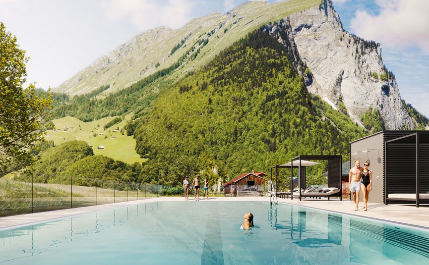 Outdoor pool with people near forested mountains under clear sky