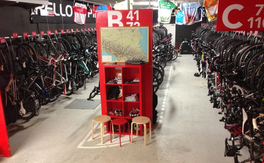 Überdachter Fahrradabstellraum mit vielen Rennrädern und roten Regalen