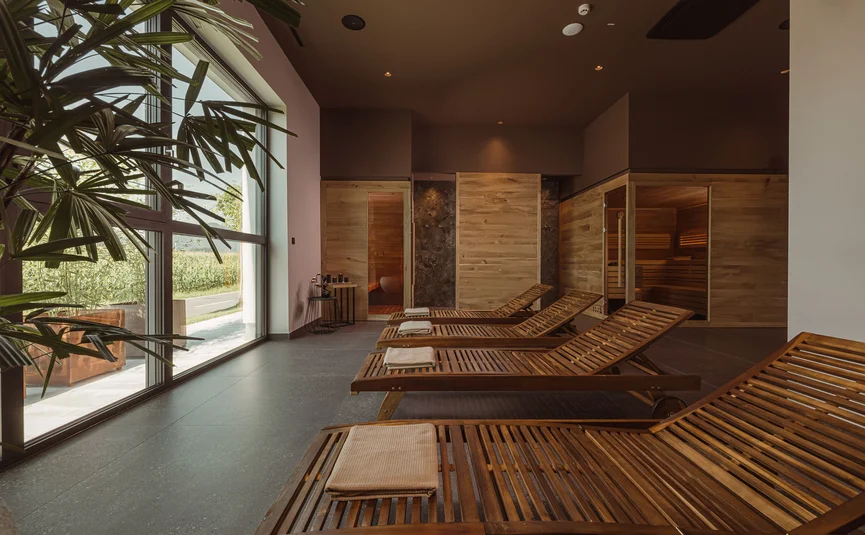 Entspannungsbereich mit Holzliegen und Sauna in hellem Raum mit Fenster