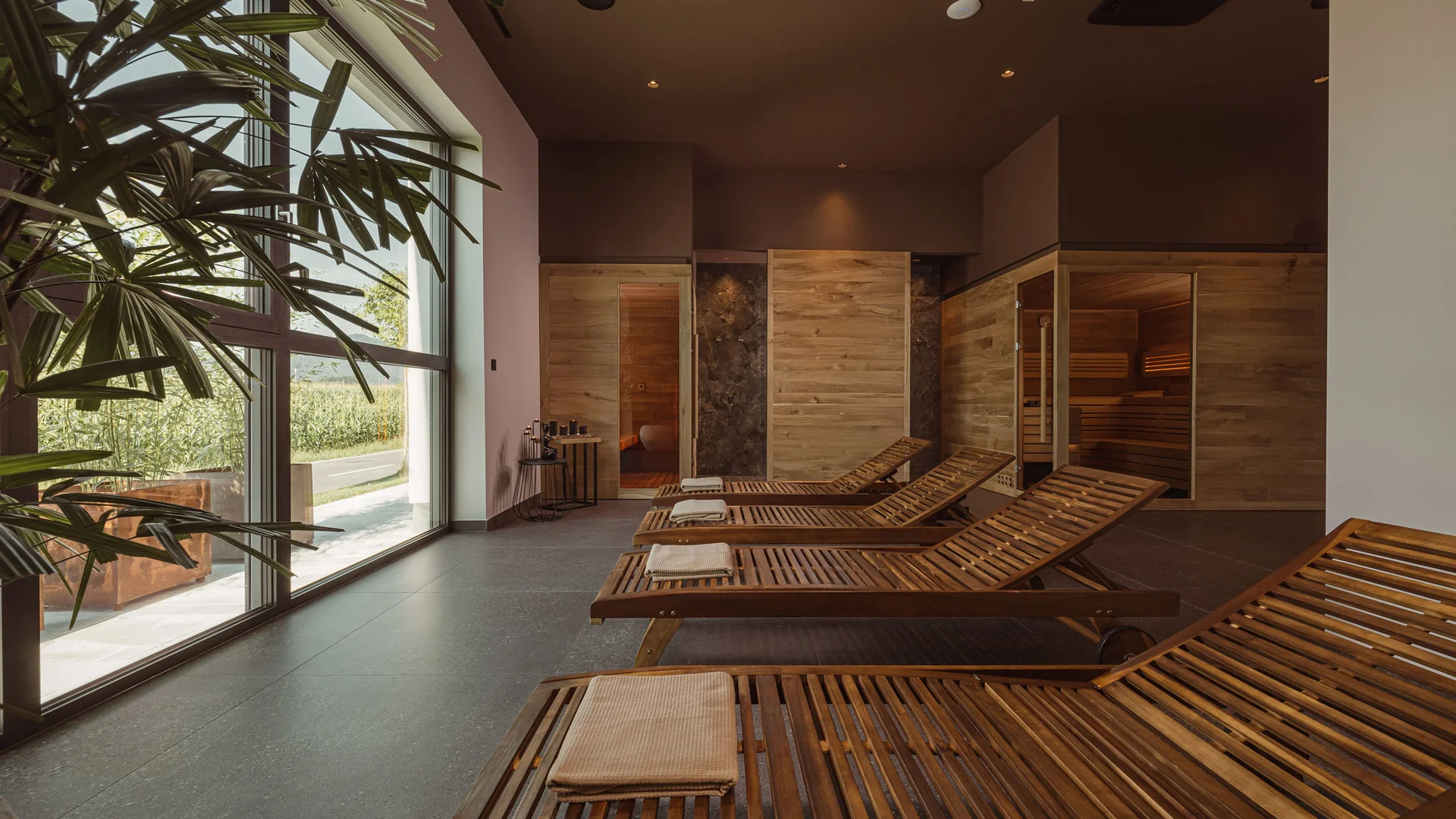 Entspannungsbereich mit Holzliegen und Sauna in hellem Raum mit Fenster
