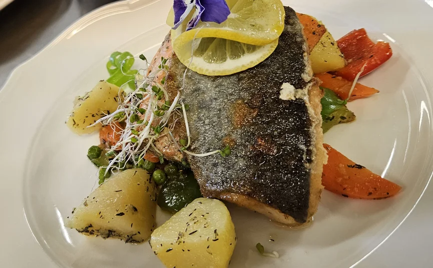 Gebratenes Fischfilet mit Zitronenscheiben, Kartoffeln und Gemüse auf weißem Teller