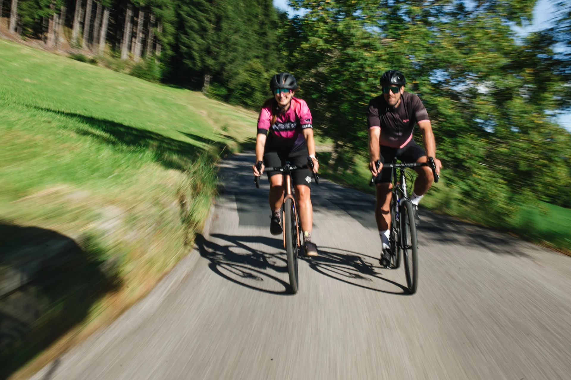 Gravelbike Holidays © Nicola Littmann Zwei Radfahrer fahren auf einem Landweg mit Bäumen und Wiesen im Hintergrund
