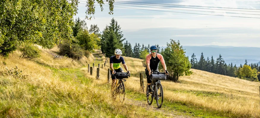 Zwei Radfahrer fahren auf einem Weg durch eine herbstliche Landschaft