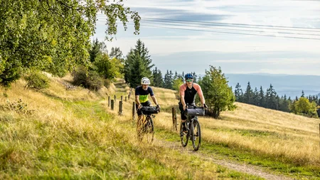 Zwei Radfahrer fahren auf einem Weg durch eine herbstliche Landschaft